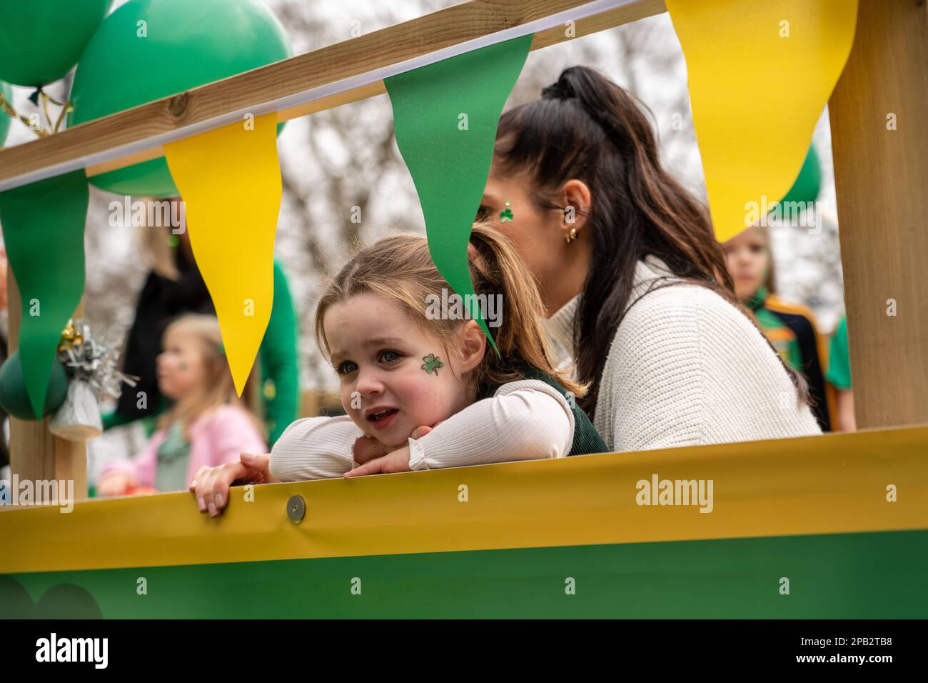 Jeff Moore - 3 year old joins her mother on a float at the St Patrick’s Day Festival parade in London. 12/03/2023 Stock Photo