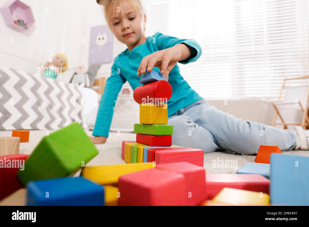 Cute little girl playing with colorful building blocks at home, focus ...