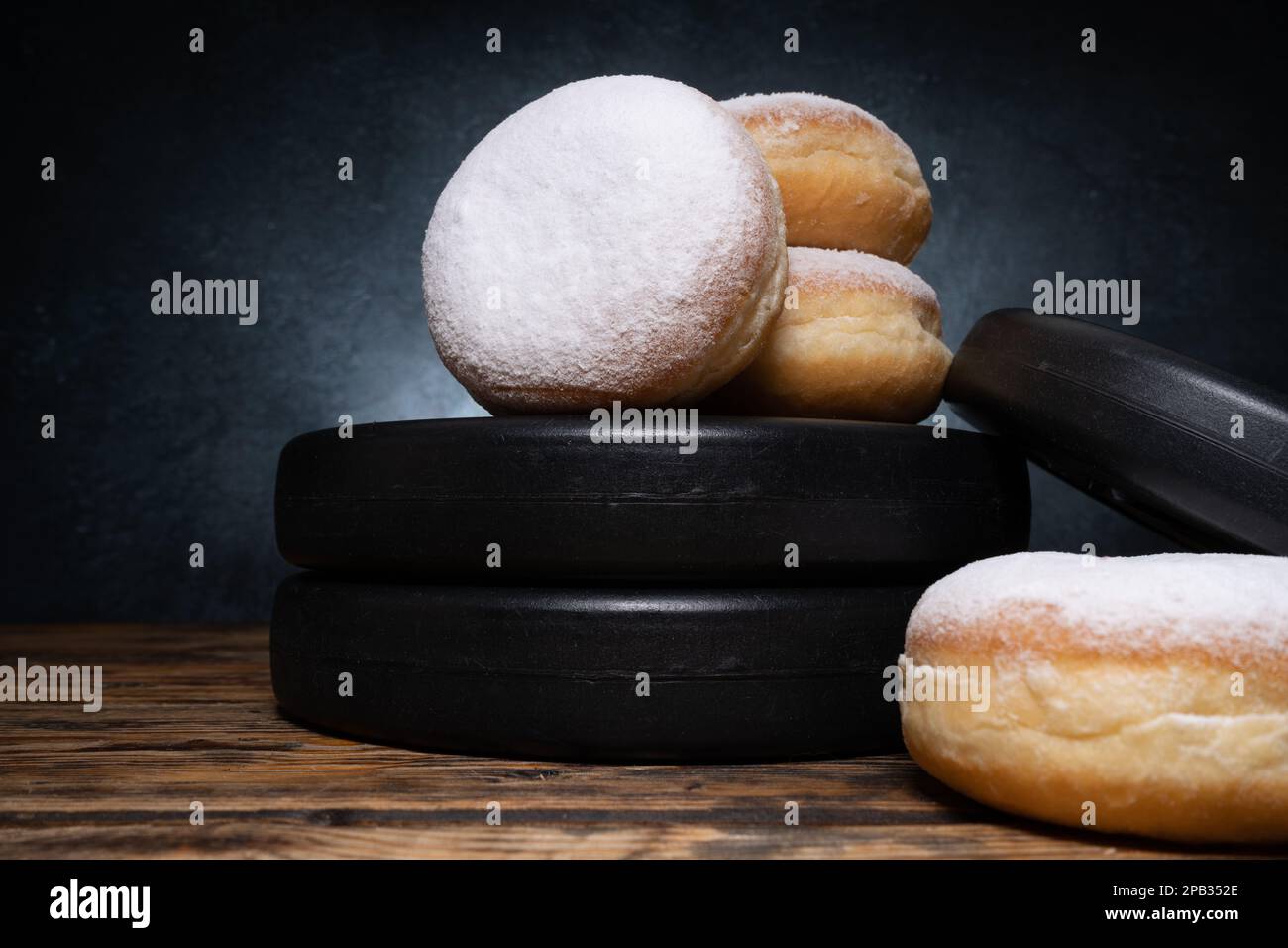 Gym dumbbells barbell weight plates and Polish pączki deep-fried doughnuts. Fat Thursday pączek in Poland. Healthy diet choice concept. Stock Photo