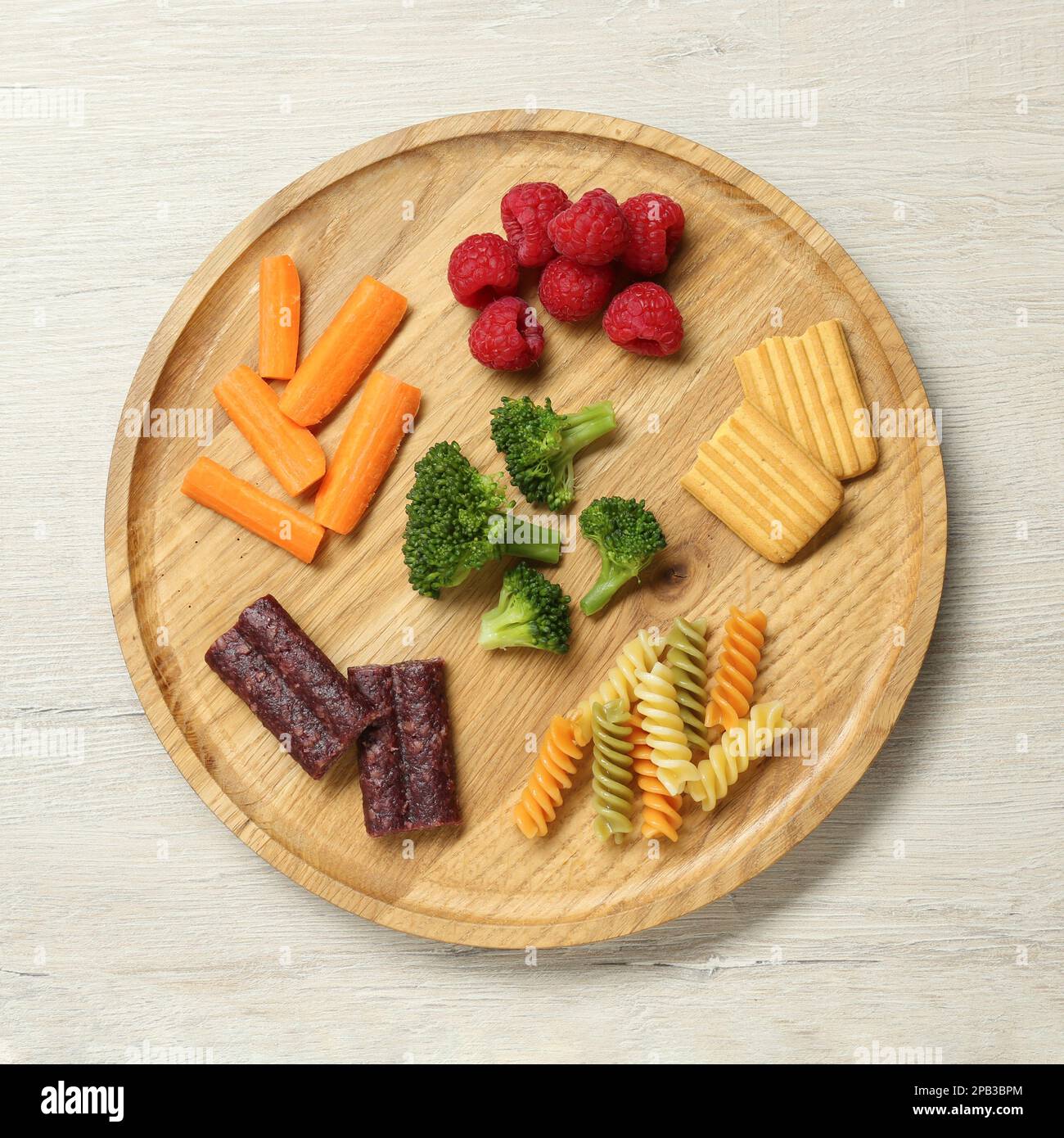 Board with different finger foods for baby on wooden table, top view