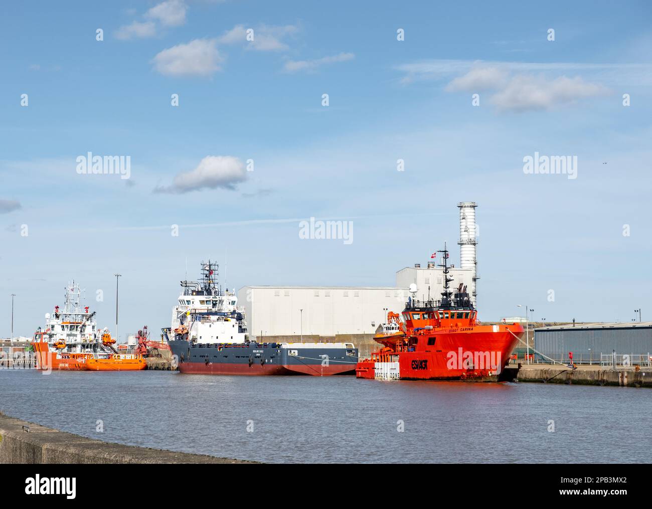 Three marine vessels moored outside industrial units on the River Yare
