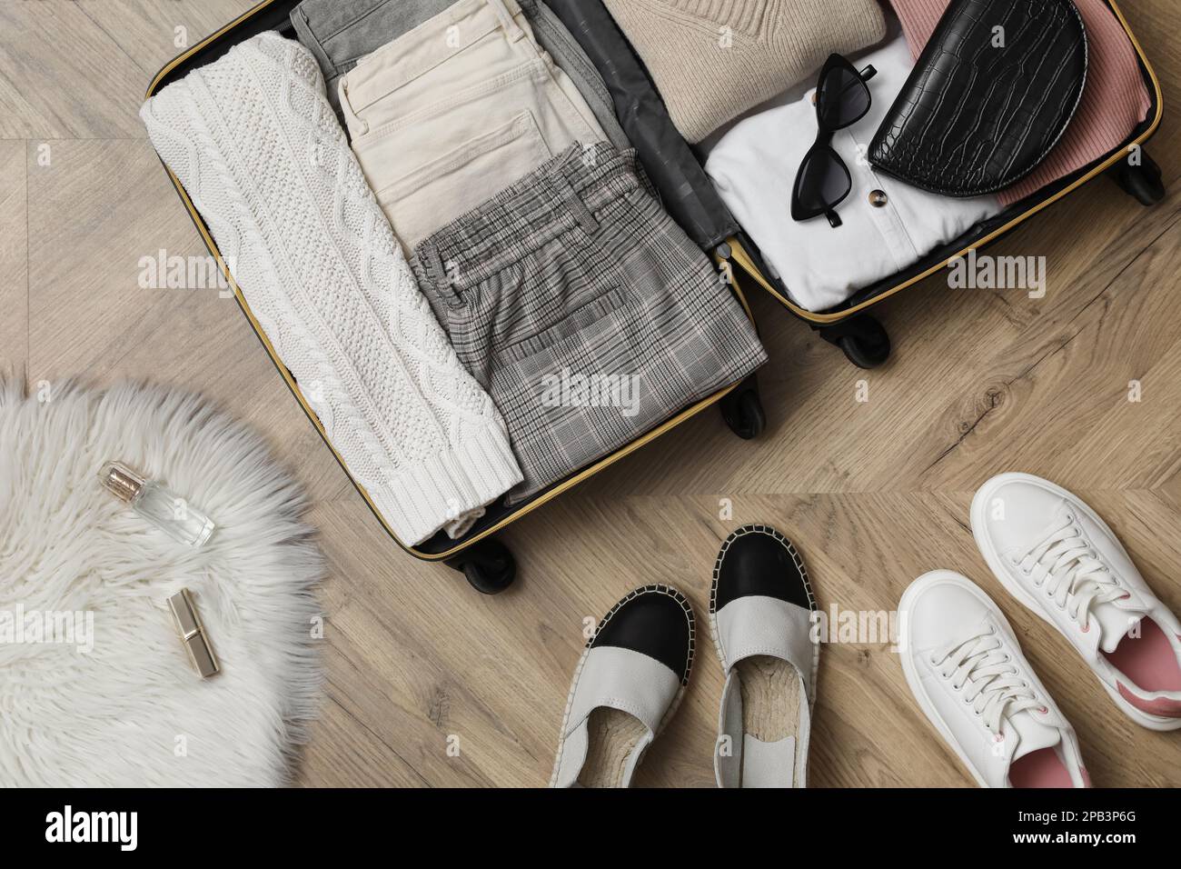 https://c8.alamy.com/comp/2PB3P6G/open-suitcase-with-folded-clothes-accessories-and-shoes-on-floor-flat-lay-2PB3P6G.jpg