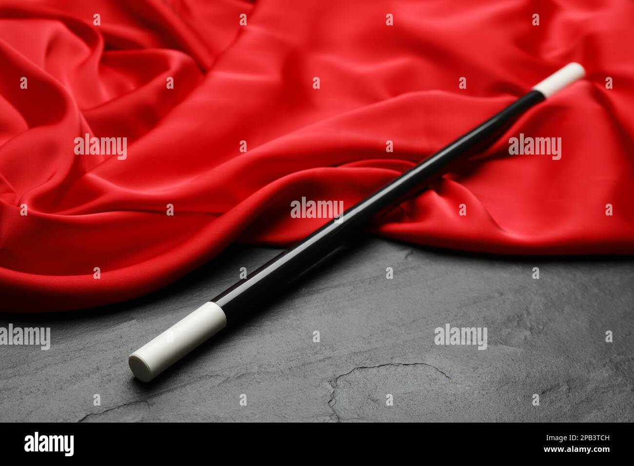 Beautiful magic wand and red fabric on black table Stock Photo