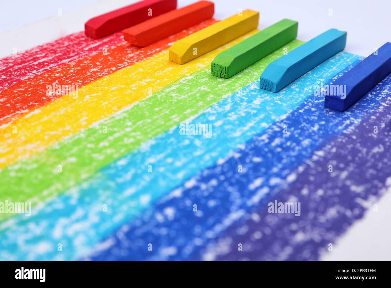 Colorful pastel chalks on rainbow painting, closeup. Drawing materials