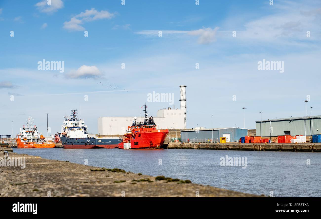 Three marine vessels moored outside industrial units on the River Yare in Great Yarmouth and