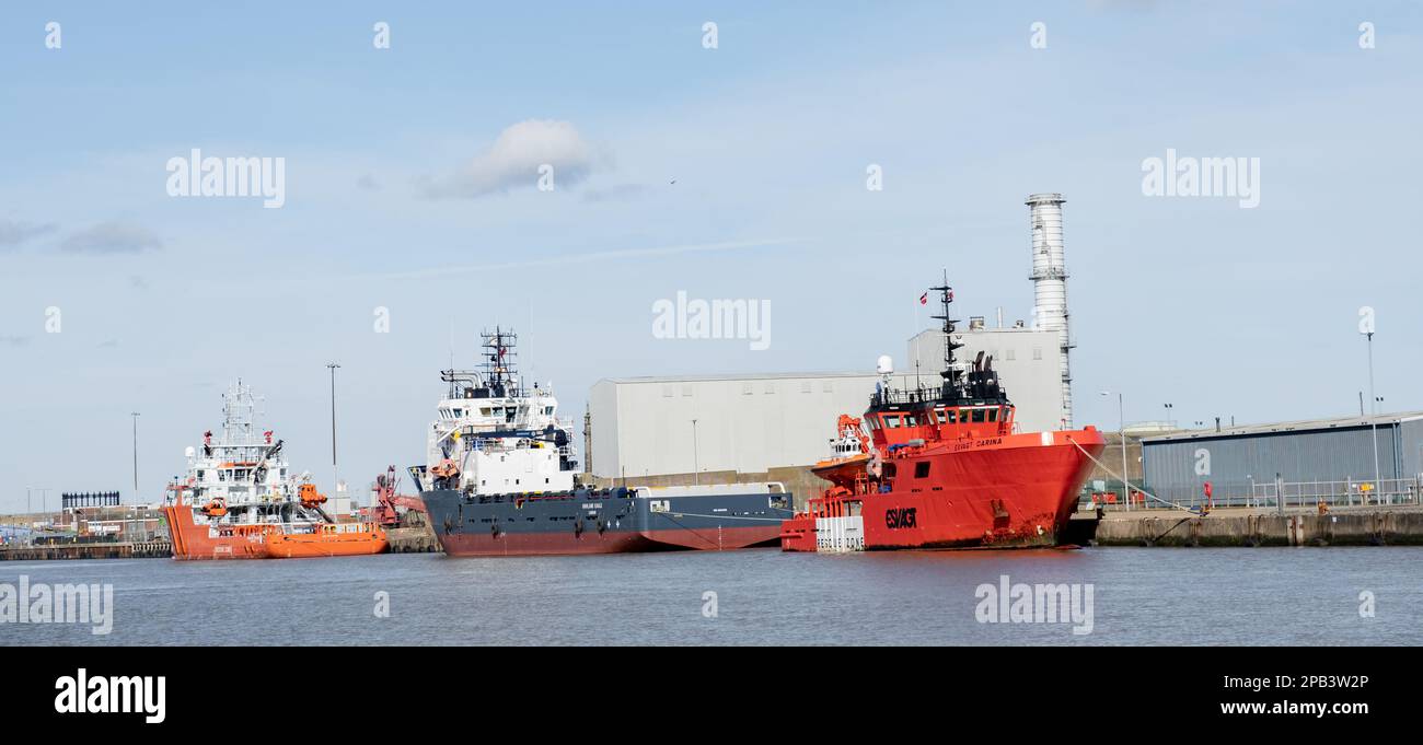 Three marine vessels moored outside industrial units on the River Yare