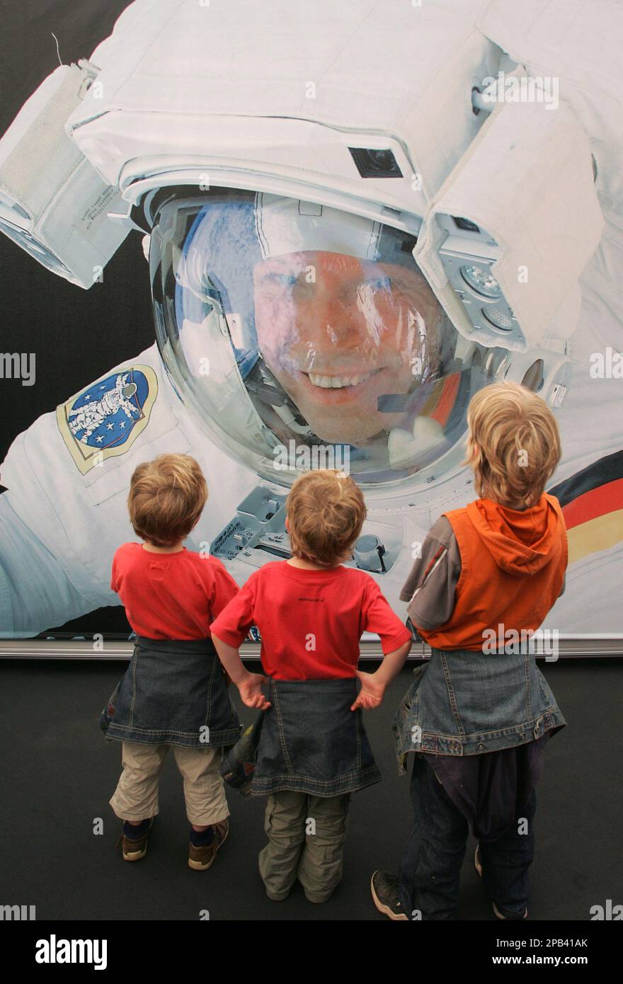 Three young visitors look at a poster showing German astronaut Thomas ...
