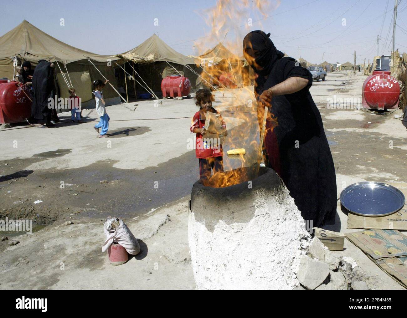 An Iraqi Shiite woman bakes bread in a camp outside of Najaf, 160 kilometers (100 miles) south of Baghdad, Iraq on Tuesday, Sept. 11, 2007. The United Nations' refugee agency estimates that about 2,000 Iraqis leave their homes every day due to violence and economic uncertainty resulting from the four-year conflict. (AP Photo/Alaa al-Marjani) Stock Photo