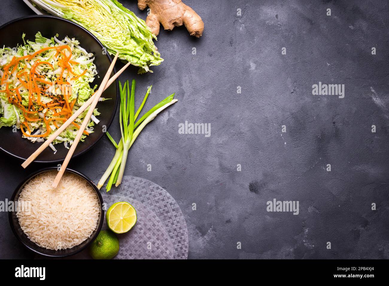 Ingredients for cooking vietnamese dinner: rice paper, rice, napa cabbage, ginger, green onion, salad. Asian cooking ingredients. Top view. Making vie Stock Photo