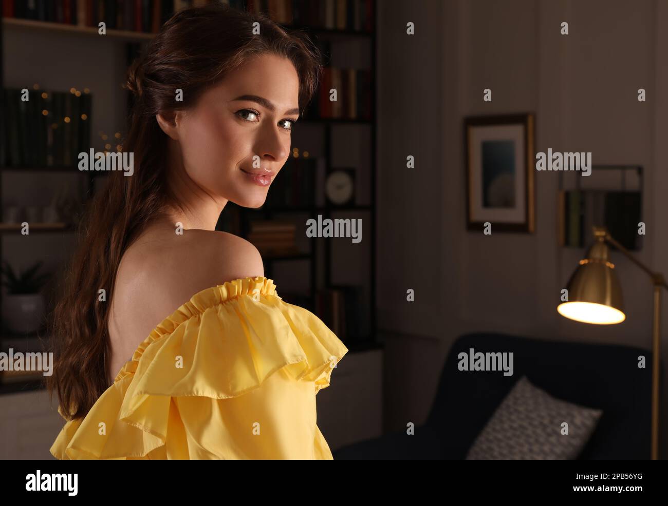 Beautiful young woman wearing yellow dress in room Stock Photo - Alamy