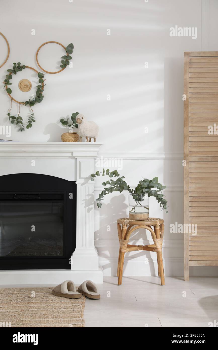 Stylish room with beautiful fireplace and eucalyptus branches Stock