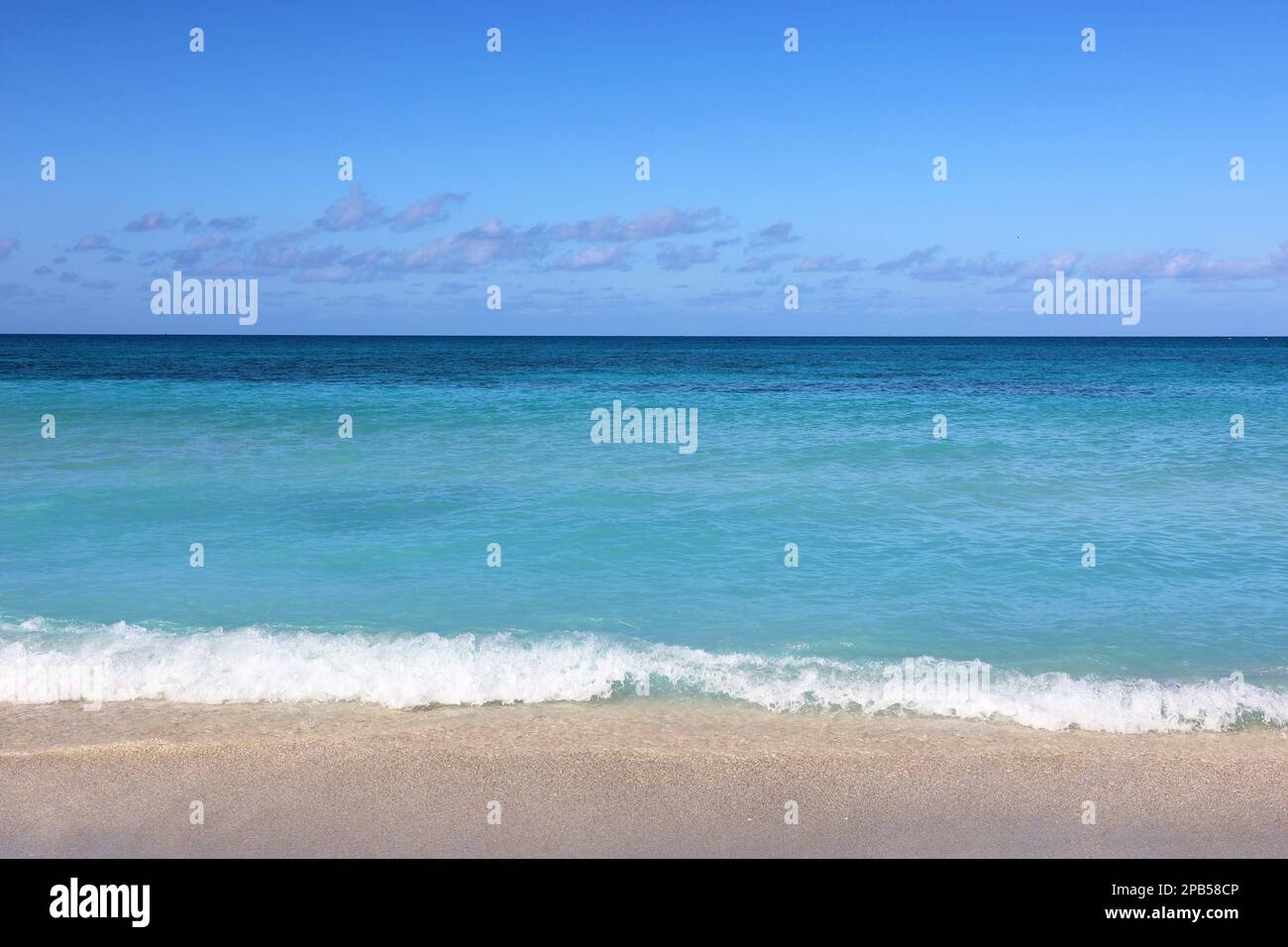 Tropical beach with white sand on a ocean, view to azure waves and sky with clouds. Caribbean coast, Background for holidays on a paradise nature Stock Photo
