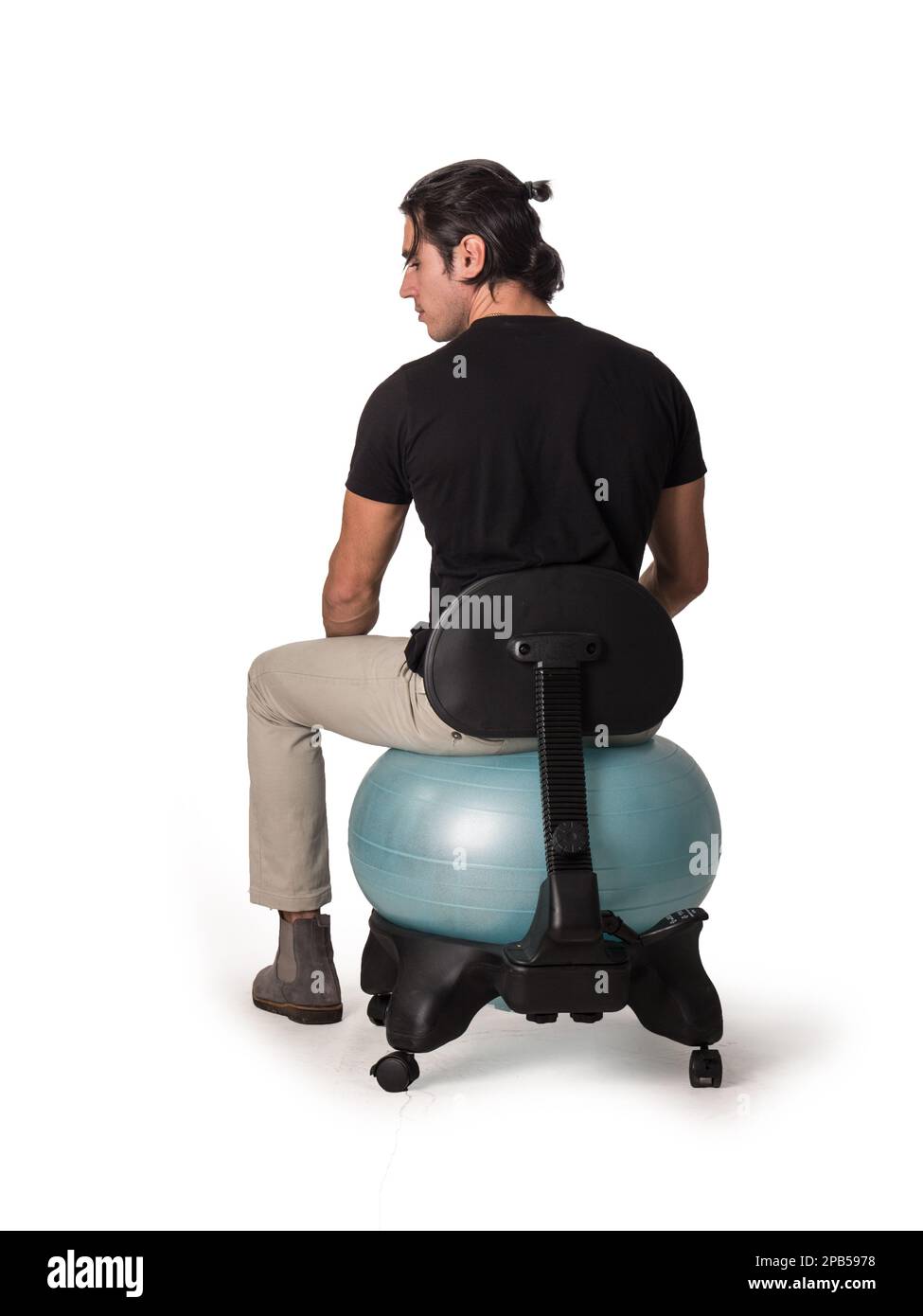 Man sitting on balance ball chair against white background Stock Photo