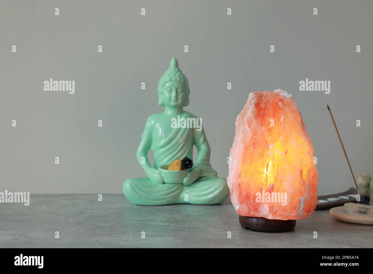 Himalayan salt lamp buddha figure incense and crystals on stone