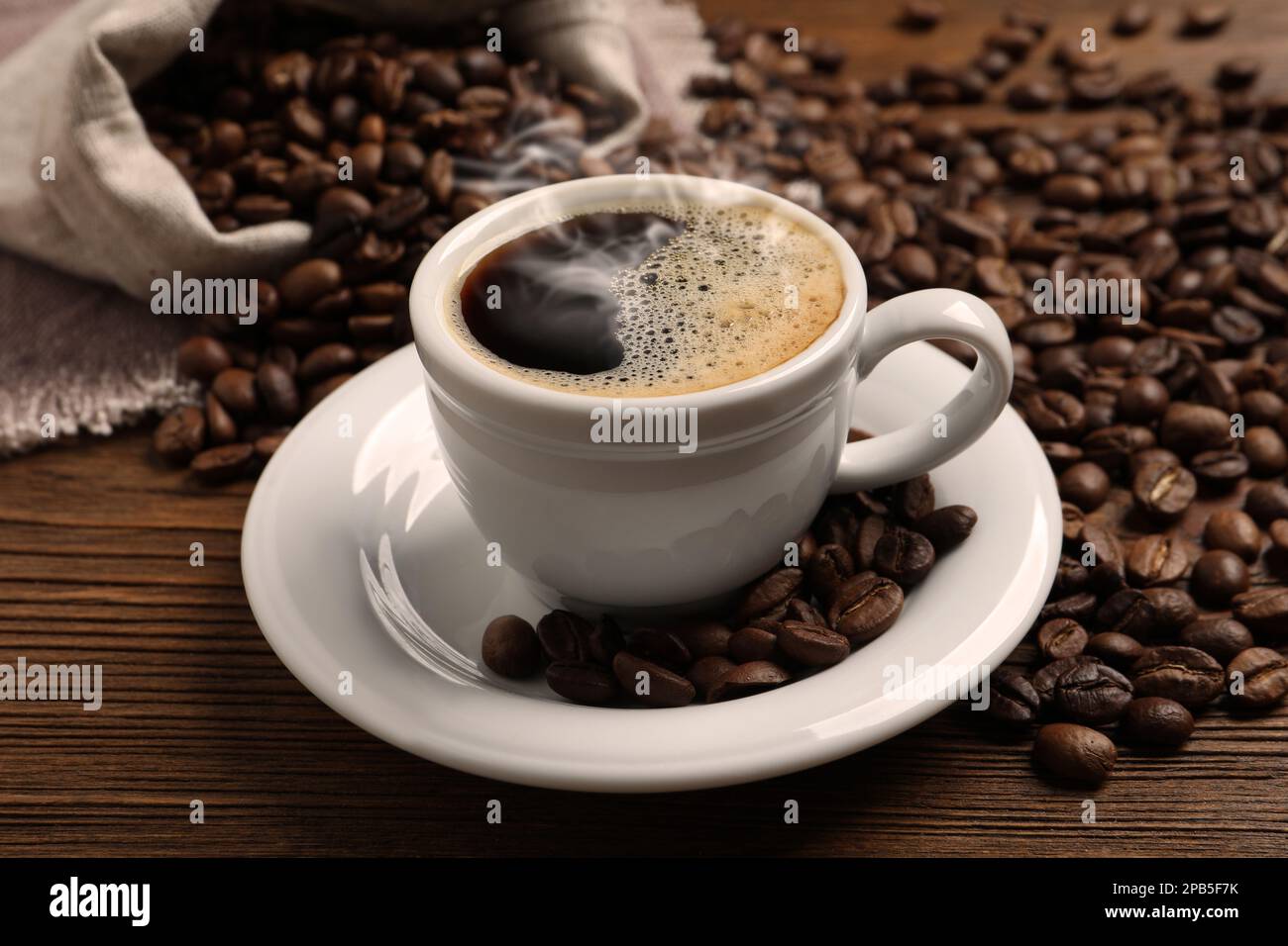 https://c8.alamy.com/comp/2PB5F7K/cup-of-aromatic-hot-coffee-and-beans-on-wooden-table-2PB5F7K.jpg