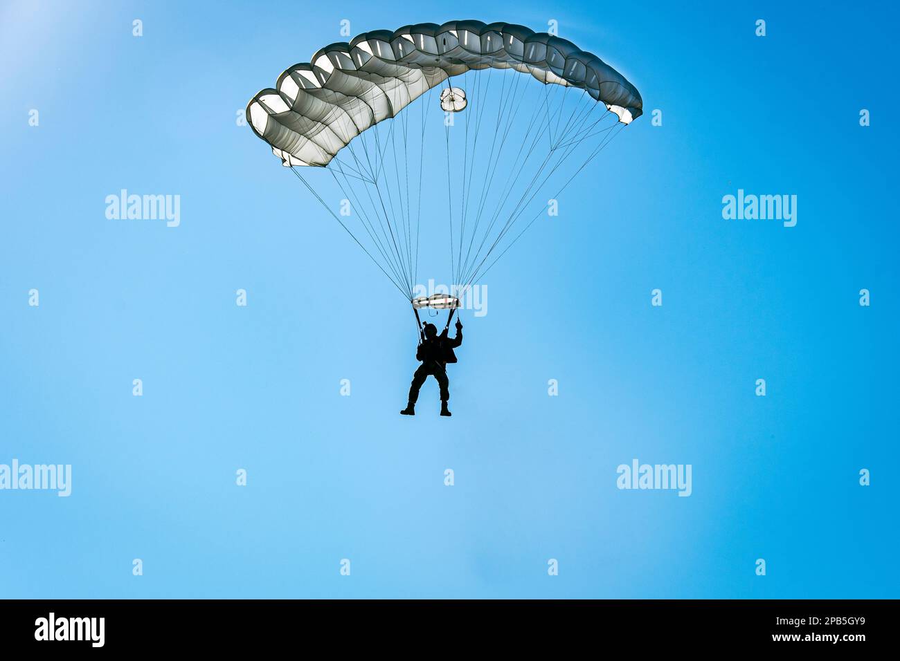 Parachutist descending with a white parachute Stock Photo