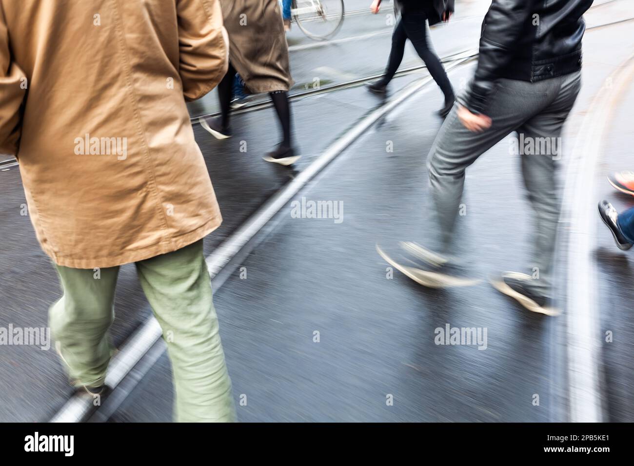 picture of people crossing a wet city street with camera made motion ...