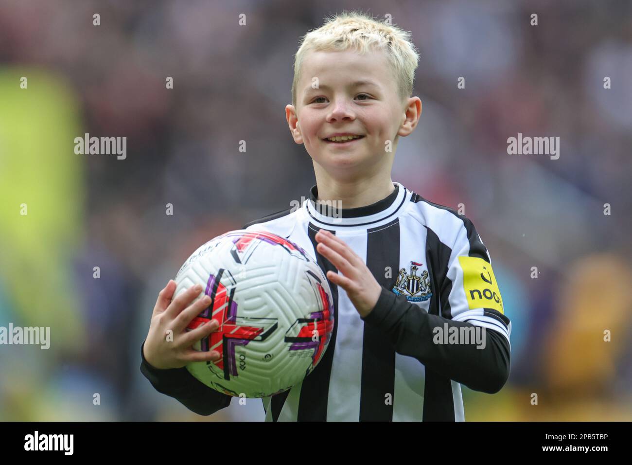 A young Newcastle United mascot with the match ball ahead of the Premier League match Newcastle United vs Wolverhampton Wanderers at St. James's Park, Newcastle, United Kingdom, 12th March 2023  (Photo by Mark Cosgrove/News Images) Stock Photo