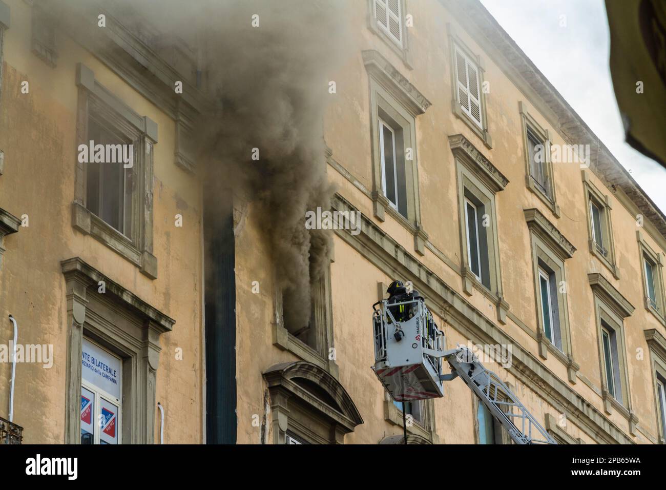 Naples, Italy - February 15th 2023 - Domestic apartment fire with smoke billowing from window. Garibaldi Square, Naples, Italy. Fire engine basket or Stock Photo