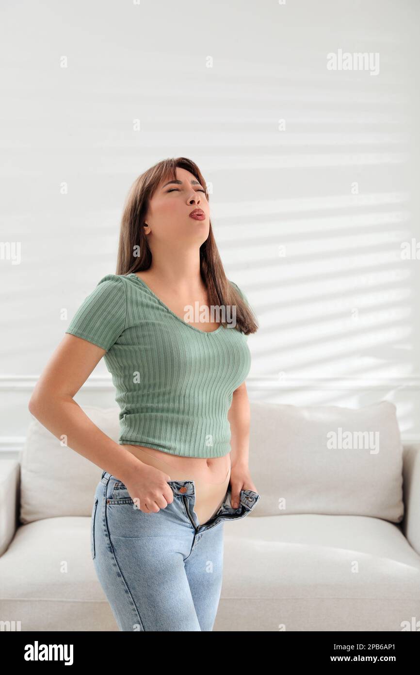Young woman struggling to put on tight jeans at home Stock Photo Alamy