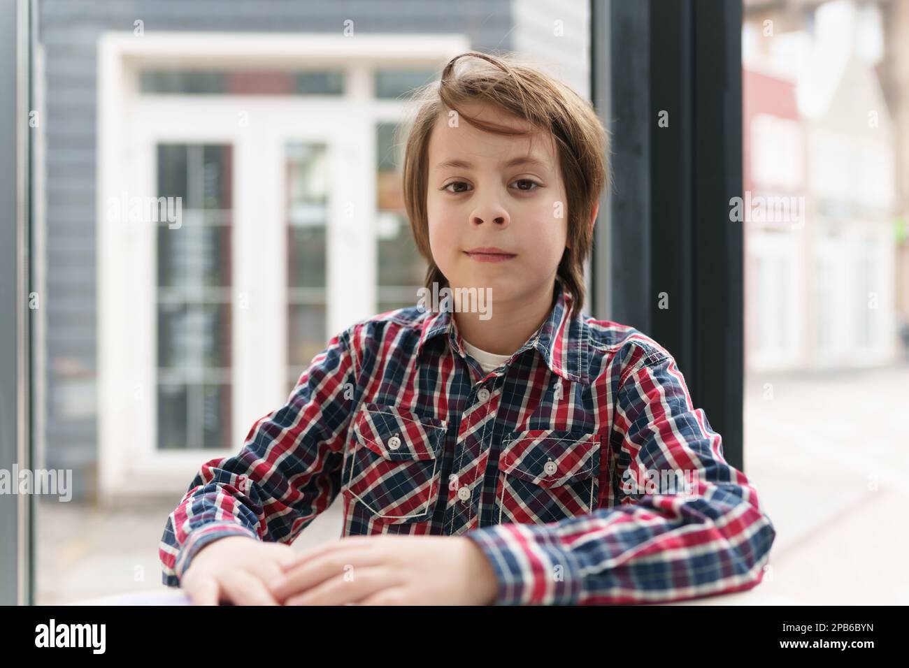 Cute elementary age boy sitting in a cafe. Portrait of pretty 11 year