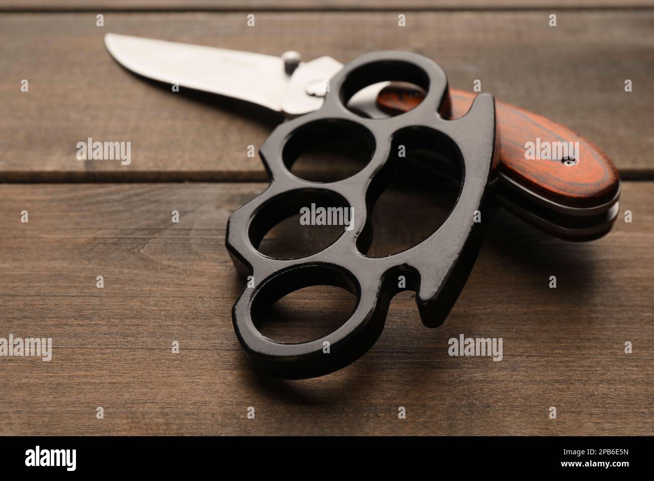 Black brass knuckles and knife on wooden background, closeup Stock Photo -  Alamy
