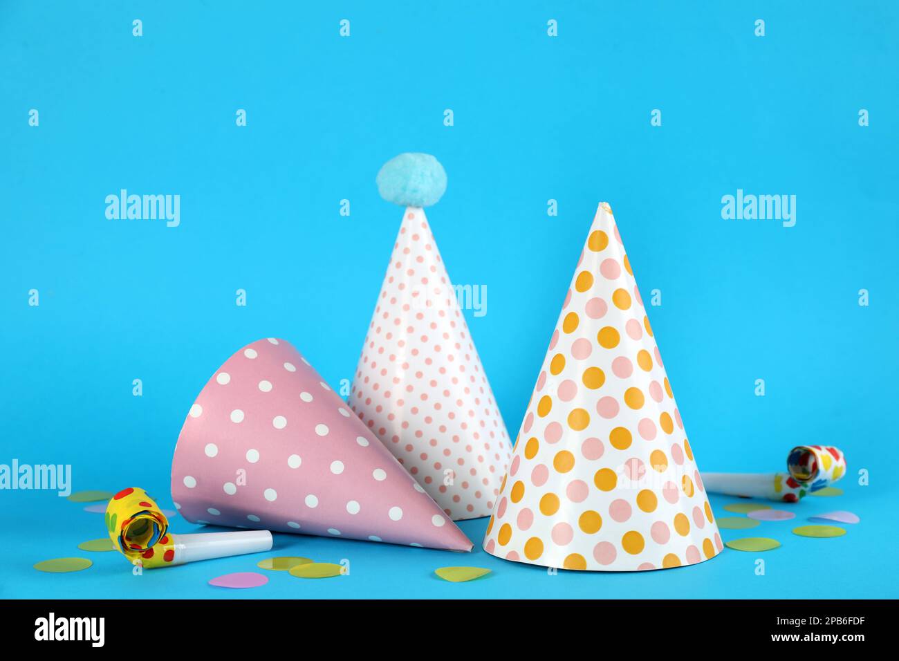 Bright party hats, horns and confetti on light blue background Stock ...