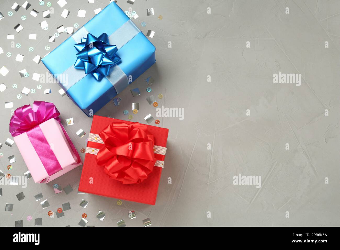 Gift boxes and shiny confetti on grey background, flat lay. Space for text Stock Photo
