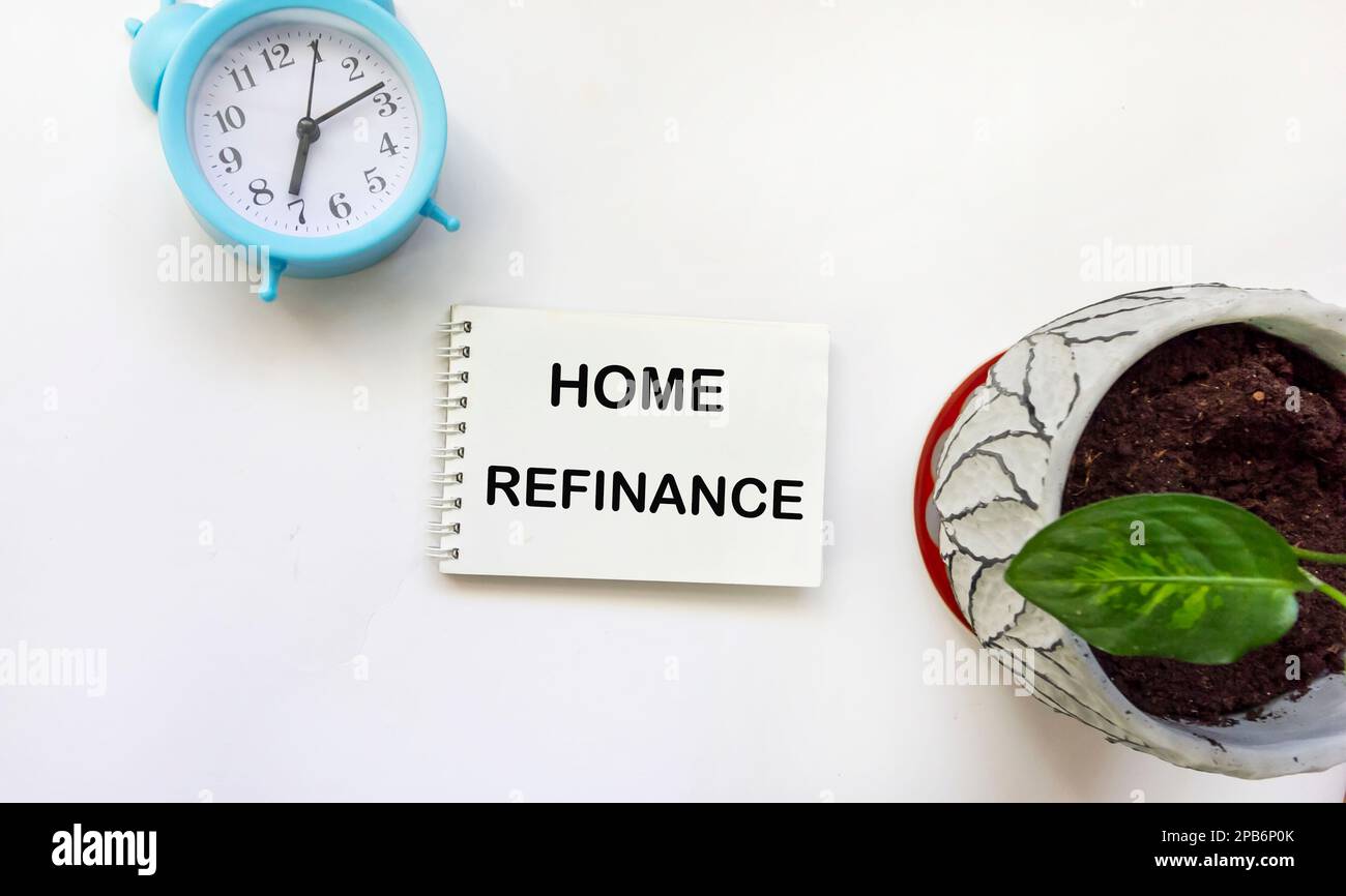 Notepad with text HOME REFINANCE with clock and flower on white background Stock Photo