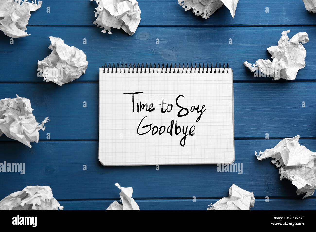 Notebook with phrase Time to say Goodbye and crumpled sheets of paper