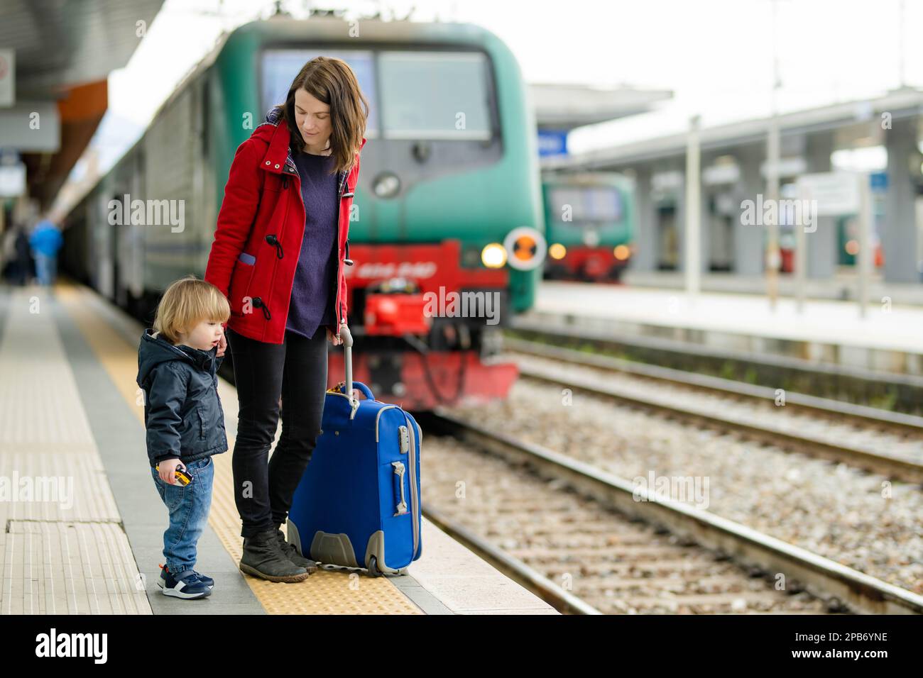 Young mother and her toddler son on a railway station. Mom and little