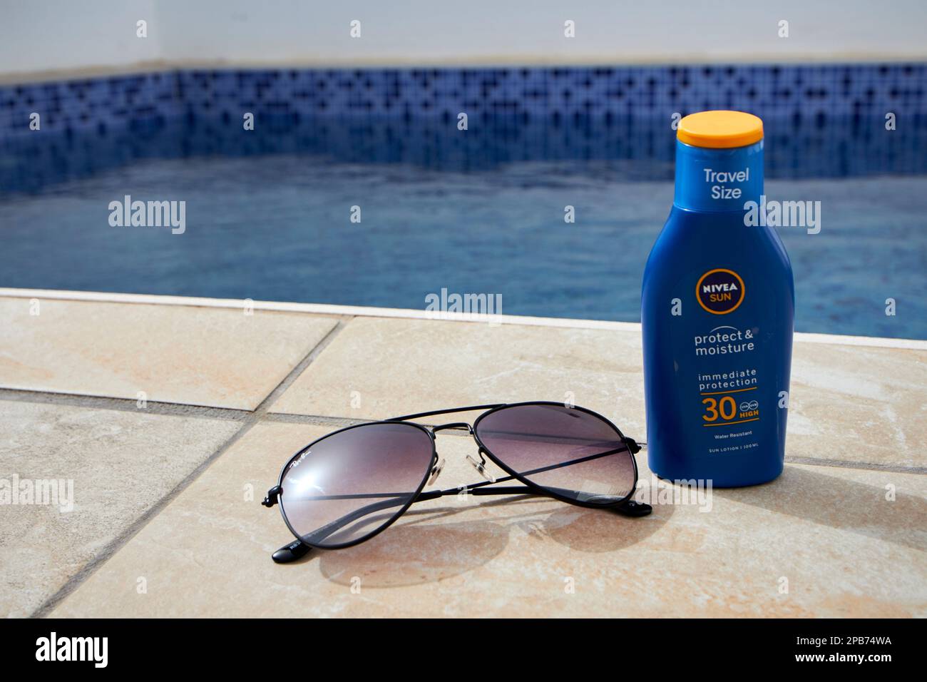 travel size sun cream and sunglasses by the side of a small pool in a villa in Lanzarote, Canary Islands, Spain Stock Photo