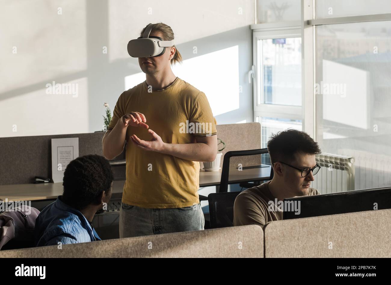 IT Development Team Working on VR Project. Man wearing VR headset, playing and touching something in the virtual world. Diverse men programmers using Stock Photo