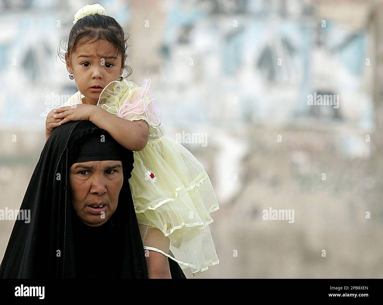 An Iraqi woman carries a little girl past a checkpoint in the Amariyah ...