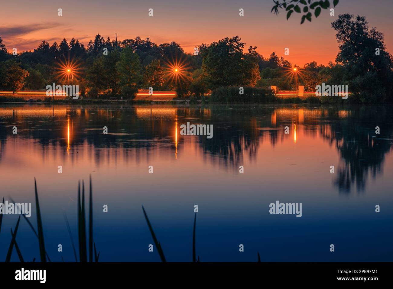 Beautiful sunset at Goettinger Kiessee. With light trails from cars and light stars from lanterns Stock Photo