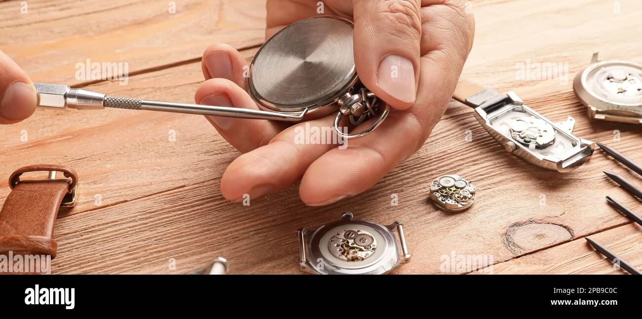 Male clock maker repairing broken clocks at table Stock Photo Alamy