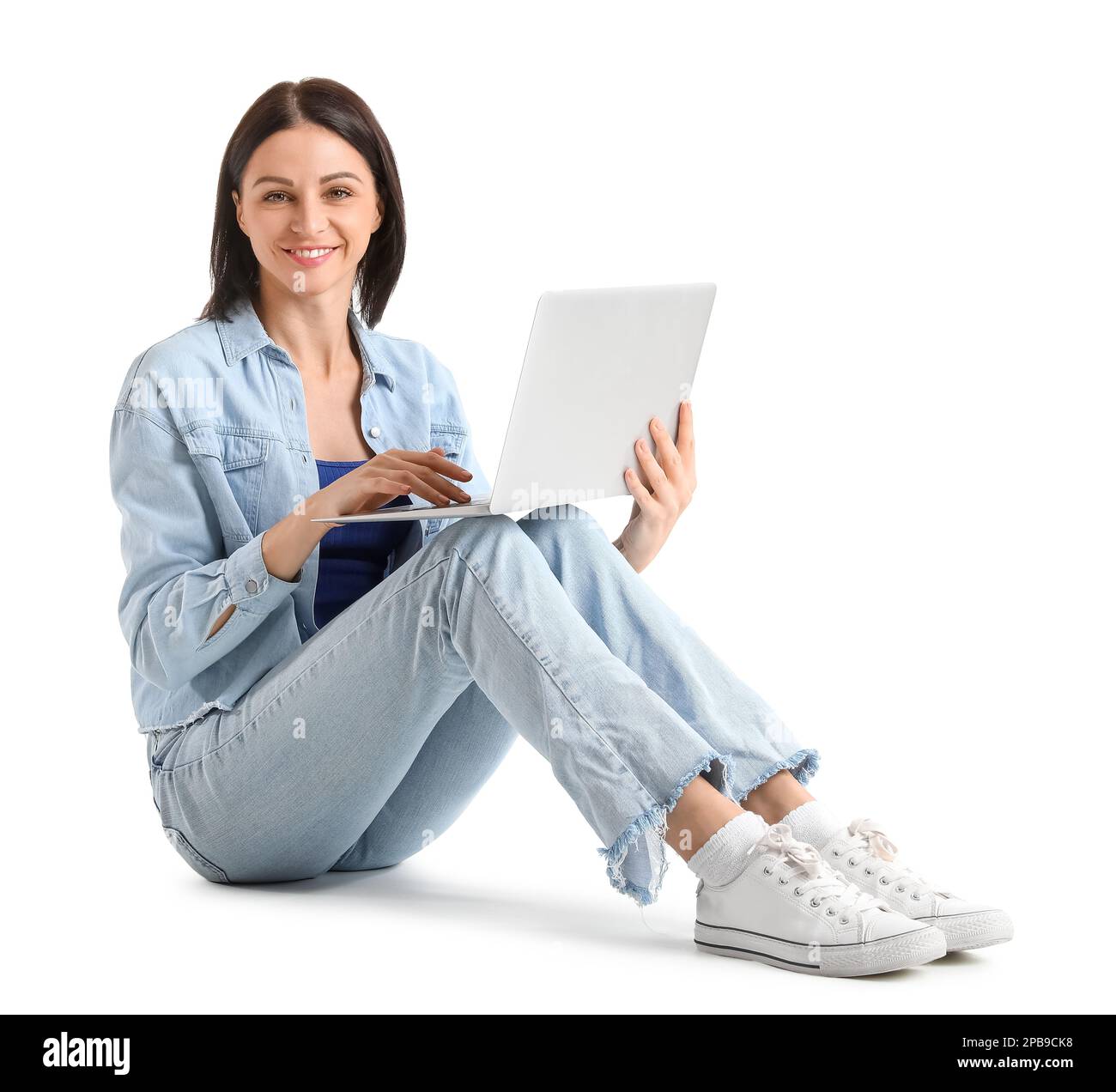Pretty young woman with laptop sitting against white background Stock ...