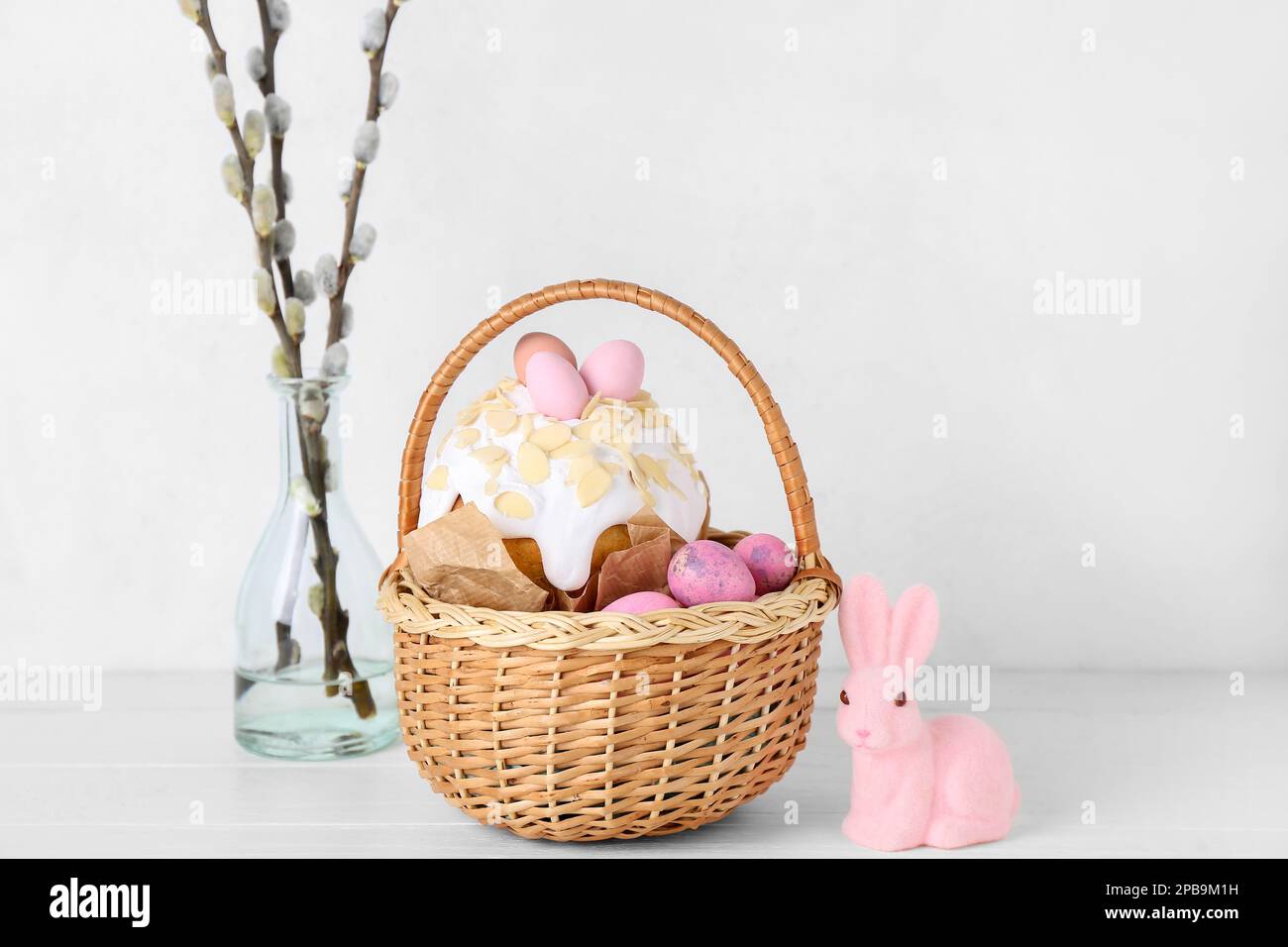 Basket with Easter eggs, cake, bunny and willow branches on white ...