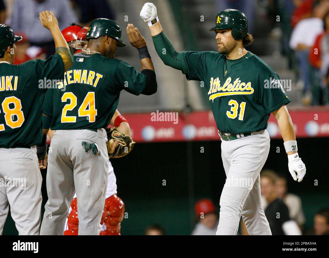 After hitting a three-run homer, Oakland Athletics designated hitter Mike Piazza, right, celebrates with teammates he drove in, Kurt Suzuki, left, and Shannon Stewart, in the fourth inning of a baseball game
