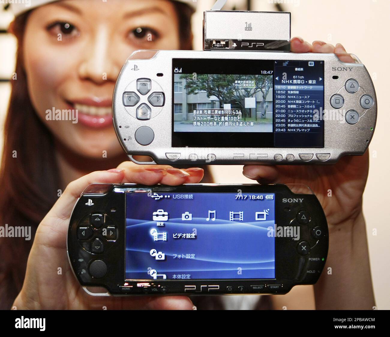 A model shows new Playstation Portable PSP-2000 during a news conference in Tokyo, Tuesday, July 17, 2007. The new handheld video-machine gets lighter and thinner and available in six colors at 19,800 yen (US$162) on Sept. 20. Also users can watch digital television broadcast on the new PSP when you attach a digital TV tuner, shown top, specially designed for the new Playstation Portable. The tuner is sold separately at 6,980 yen ($57). (AP Photo/Itsuo Inouye) Stock Photo