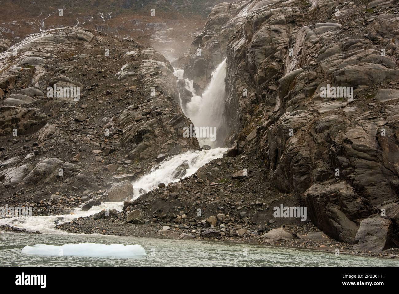 Waterfall and ice growler, rocky cliffs near Jorge Montt Glacier, Patagonia Stock Photo