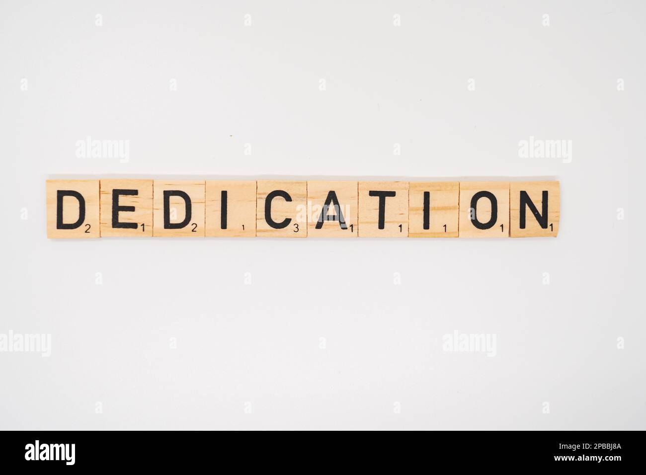 Wooden title spelling the word dedication isolated on a white background Stock Photo