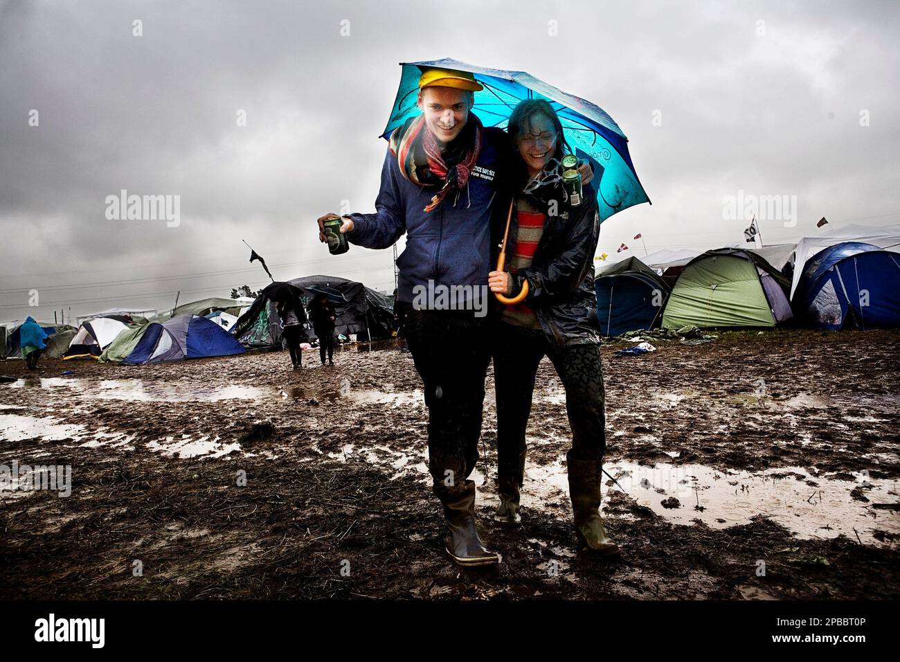 A couple walk in the mud at Roskilde Festival 2007 in Roskilde, Denmark, on Wednesday, July 4, 2007. Heavy rain has turned the music festival site into a chaos of mud, and many festival participants left the festival Thursday night, although many are sticking it out. (AP Photo / Ditte Valente, ROCKPHOTO/POLFOTO) ** DENMARK OUT ** Stock Photo