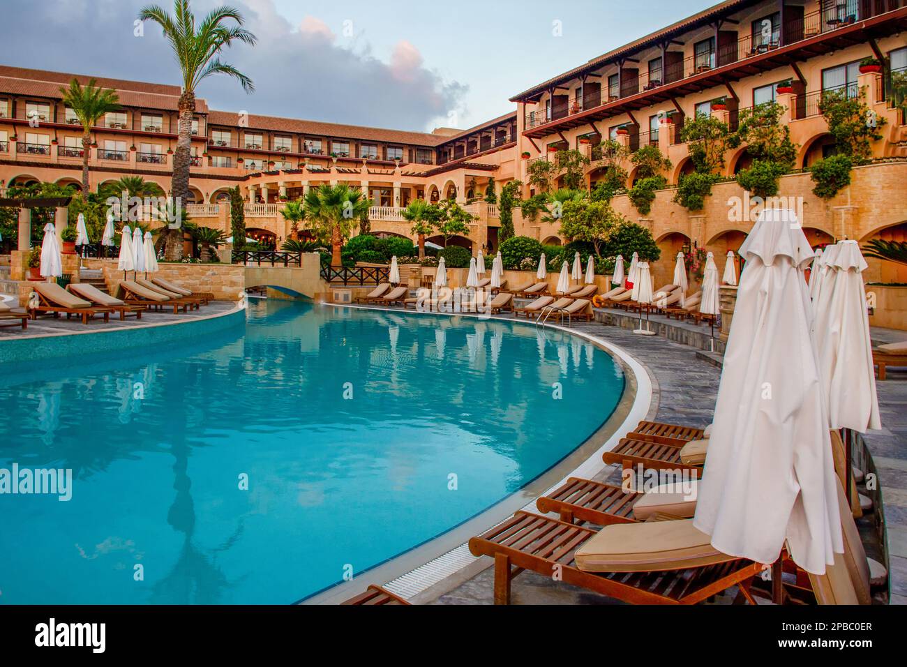 Pool in 5 star hotel in Paphos and idyllic garden with palm trees lounge chairs and folded