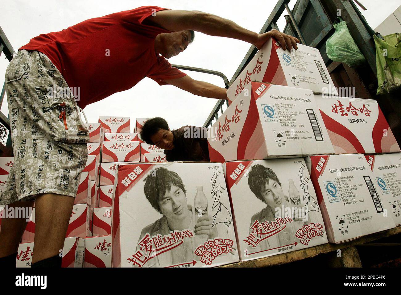 Workers load boxes of water bottles at the distribution center of ...