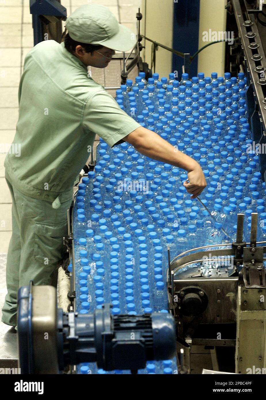 A worker arranges water bottles for packing at the production line of ...