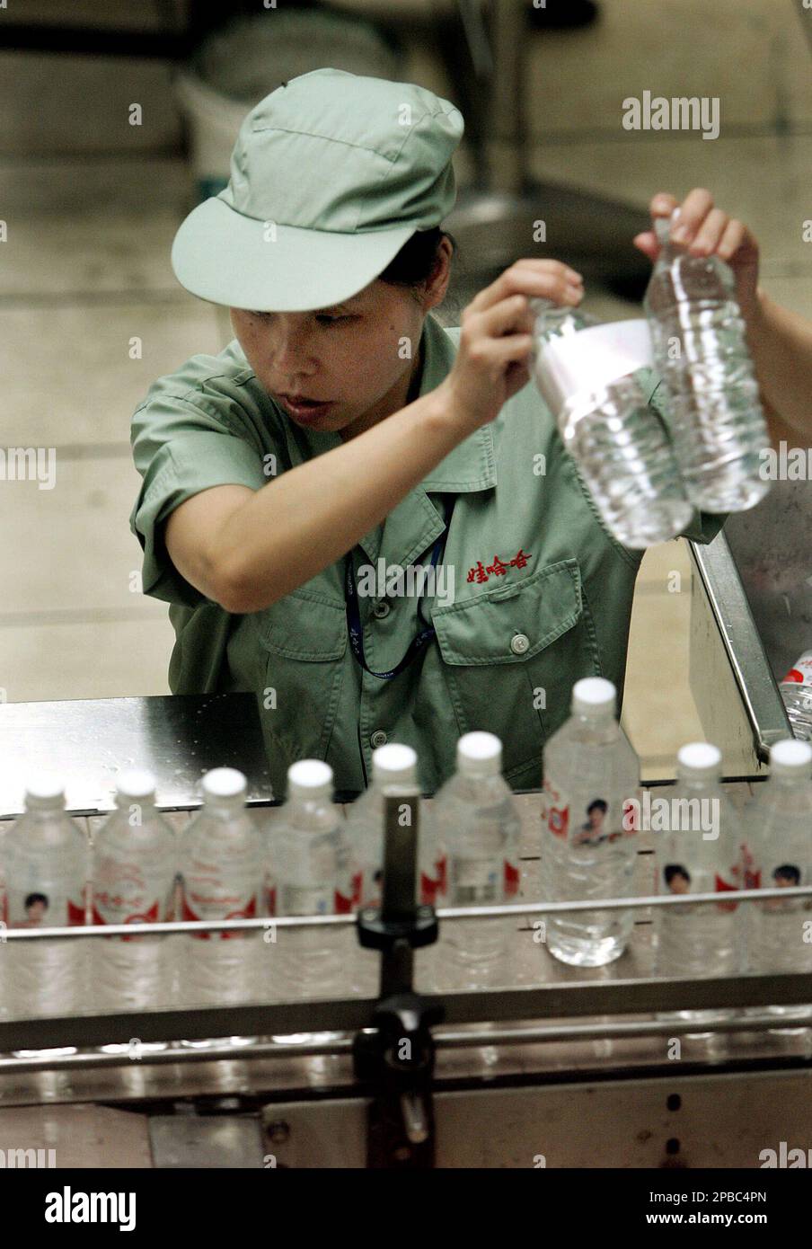 A worker selects water bottles at the production line of Wahaha Tuesday ...