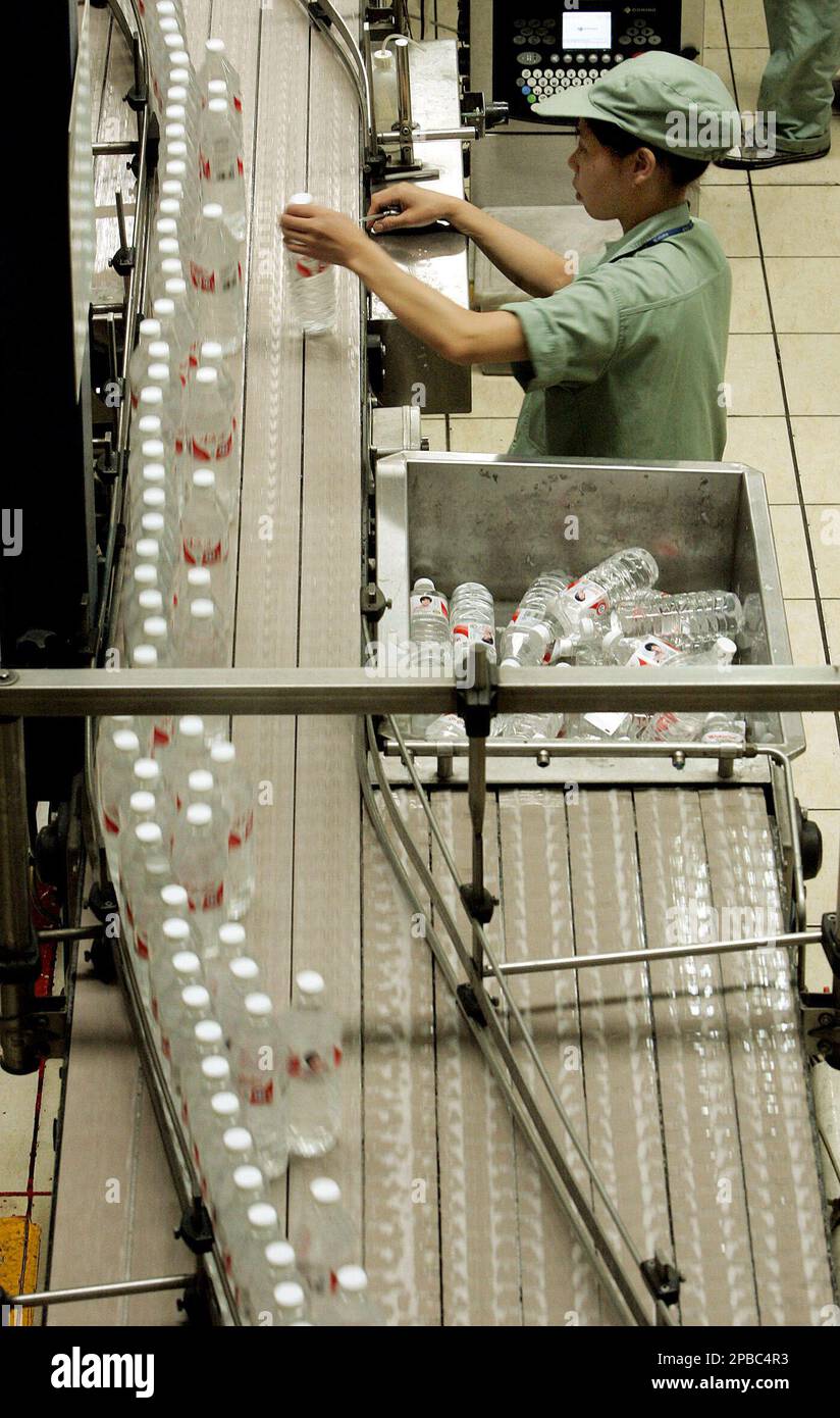 A worker selects water bottles at the production line of Wahaha Tuesday ...