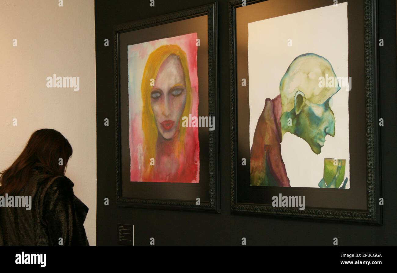 A visitor looks at paintings of US rock musician Marilyn Manson in a ...