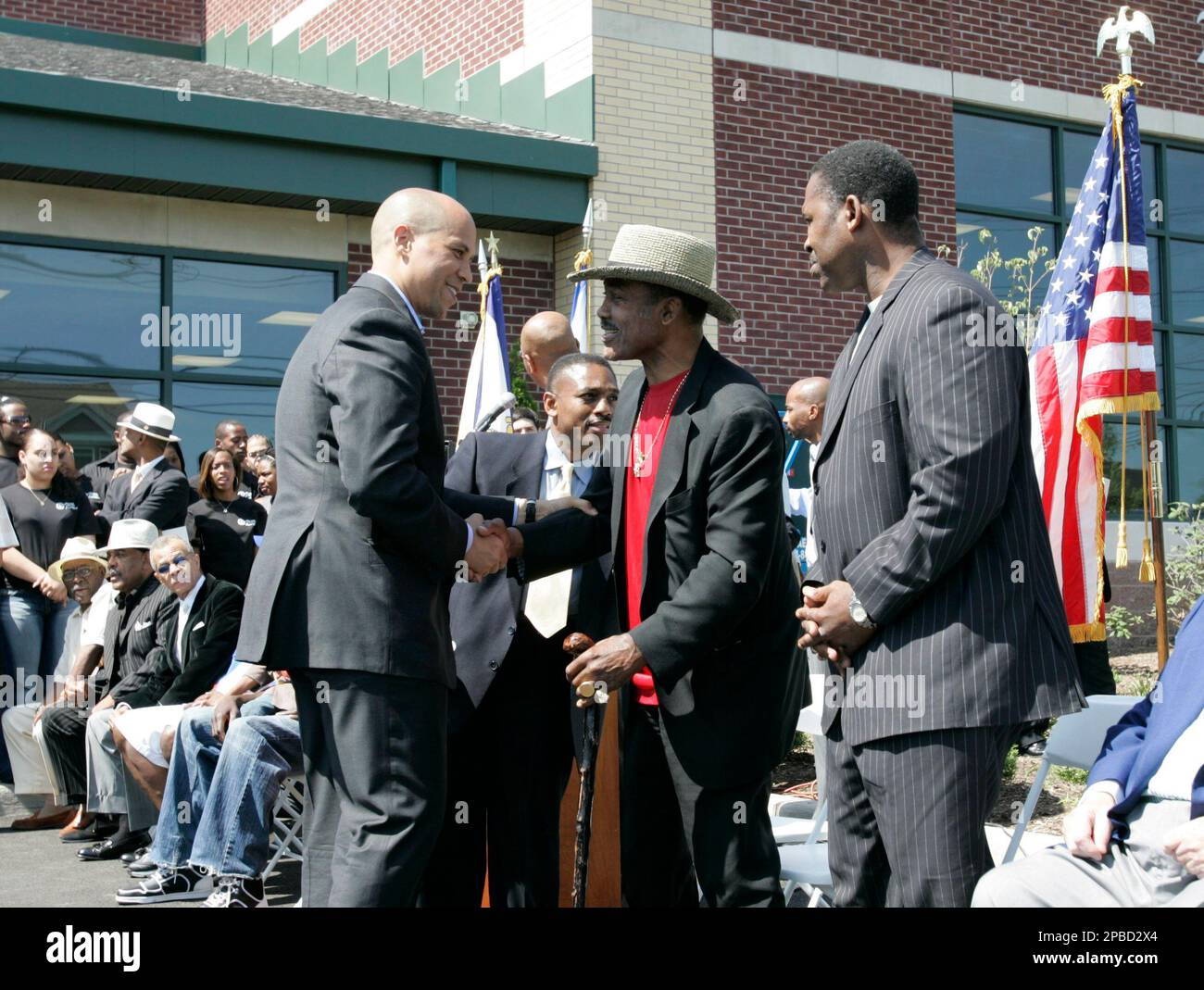 Newark Mayor Cory Booker, left standing, greets former heavyweight champion Joe Frazier, center, and his son, former boxer Marvis Frazier, during the opening of a new recreation center in Newark, N.J., Thursday, June 21, 2007. The new facility, dubbed the "Club House," will offer a recording studio, computer lab with graphic design instruction, a fitness gym with boxing, karate and dance. (AP Photo/Mike Derer) Stock Photo